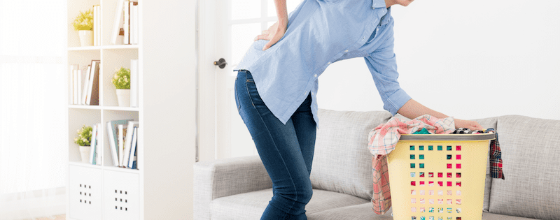 Frau mit Rückenschmerzen bei der Hausarbeit
